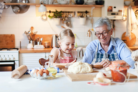 A granddaughter and grandparent making cookies together in a kitchen
