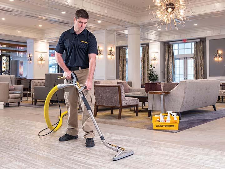 Stanley Steemer technician deep cleaning the laminate floor of a hotel lobby