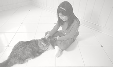 Young girl sitting on a tile floor with her cat. 