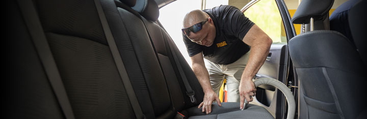 Stanley Steemer technician vacuums car upholstery