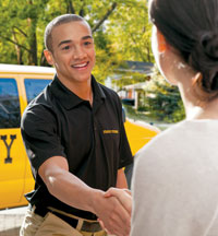 Smiling Stanley Steemer technician warmly greets customer at the front door on a sunny spring day