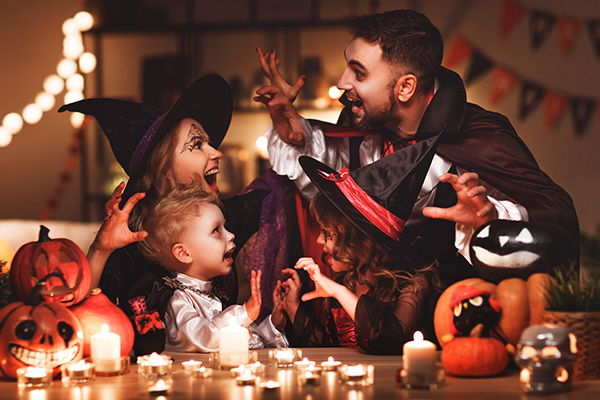 A family dressed in Halloween costumes and having fun in their kitchen decorated for the fall season
