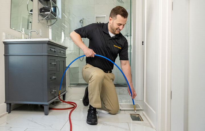 Stanley Steemer technician cleaning air duct vent in bathroom