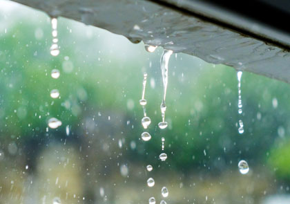 Rainwater from a hurricane or tropical storm drips off the side of a home