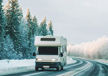 An RV driving through a winter wonderland