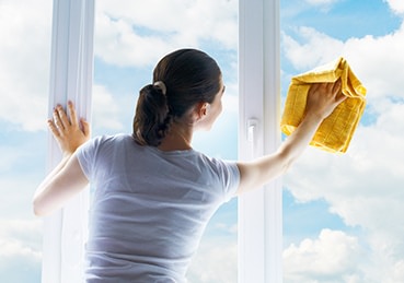 Woman wiping down a window with a towel. 