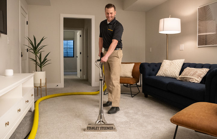 Stanley Steemer technician deep cleaning living room carpet flooring